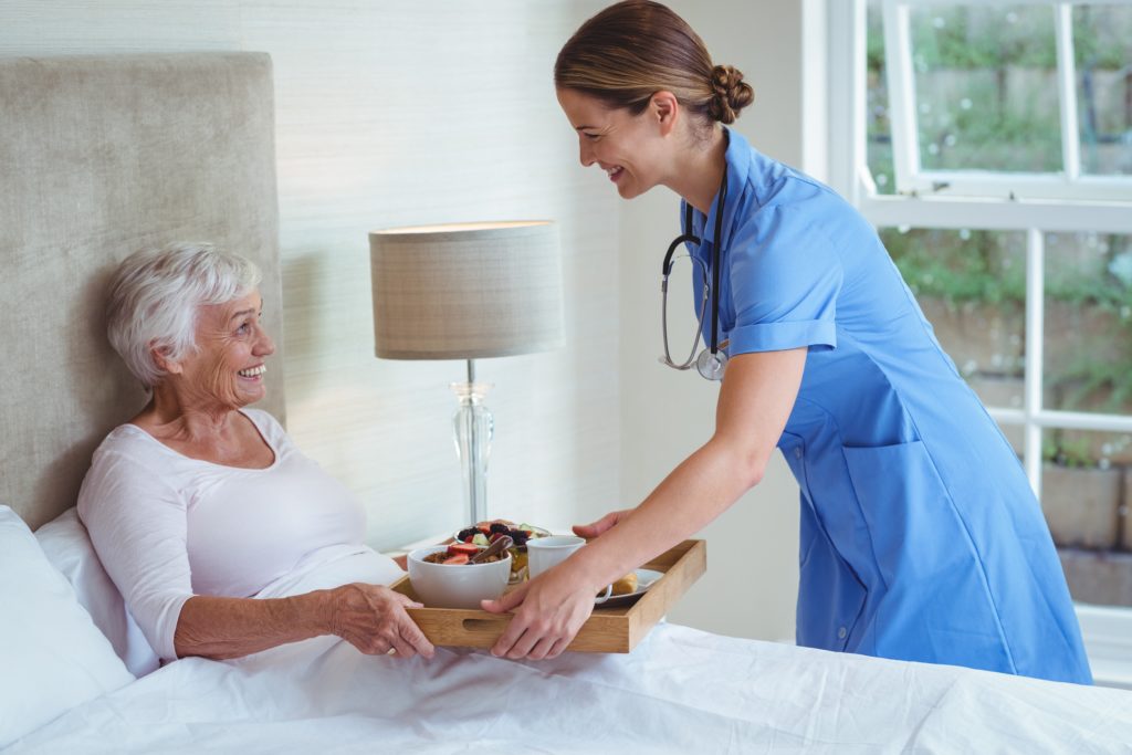 Smiling nurse giving food to senior woman